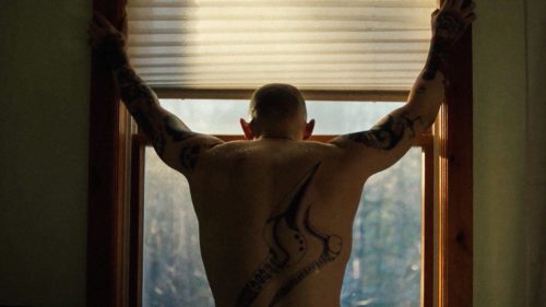 Hauptdarsteller Jamie Bell schaut aus Fenster, man sieht seinen tätowierten Rücken