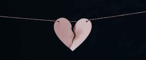 Ein zerrissenes Papierherz auf einem Faden