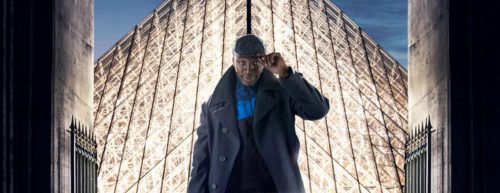 Hauptfigur Lupin, wie sie sich vor dem Louvre mit wissendem Lächeln an die Kappe greift