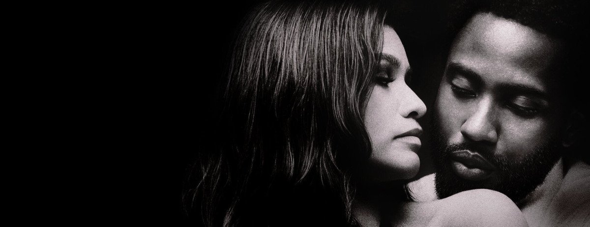 Malcolm nimmt Marie von hinten in den Arm, sie schaut Malcolm über die Schulter an