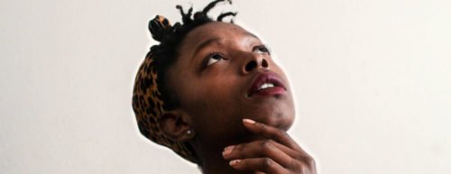 Eine Frau greift sich an das Kinn und schaut nachdenklich nach oben