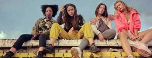 Die vier Protagonistinnen sitzen auf einer Mauer und schauen in die Kamera