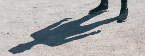 Ein Schatten einer Person, oben rechts sieht man deren Füße