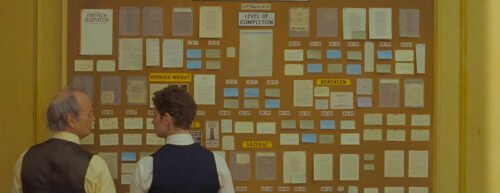 Zwei Verleger stehen vor einer Pinnwand voller Ideen für die Zeitung The French Dispatch