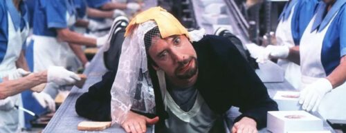 Filmfigur Gord liegt auf einem Fließband, umgeben von Käse, weil er ein Käsesandwich sein möchte